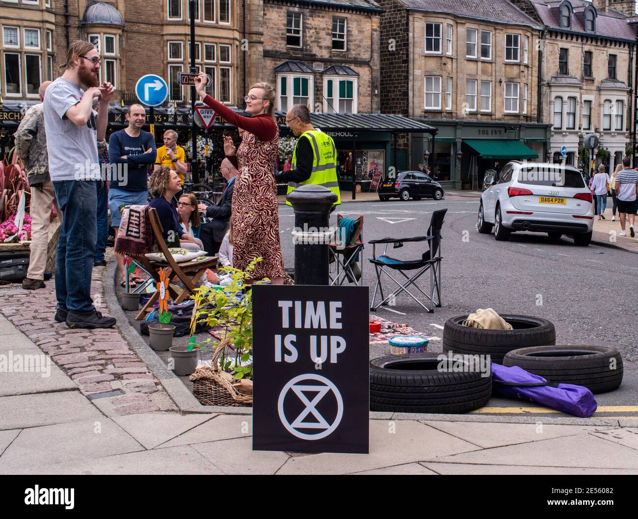Members of Extinction Rebellion smile and interact behind a Time Is Up sign while staging a protest to reclaim public areas in the centre of Harrogate. Stock Photo