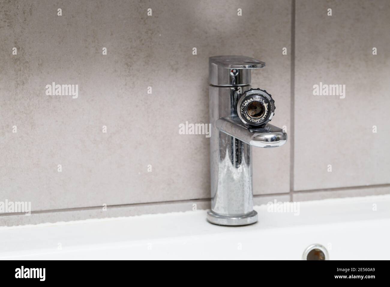 Broken tap in the bathroom sink. Splashing water from a silver faucet
