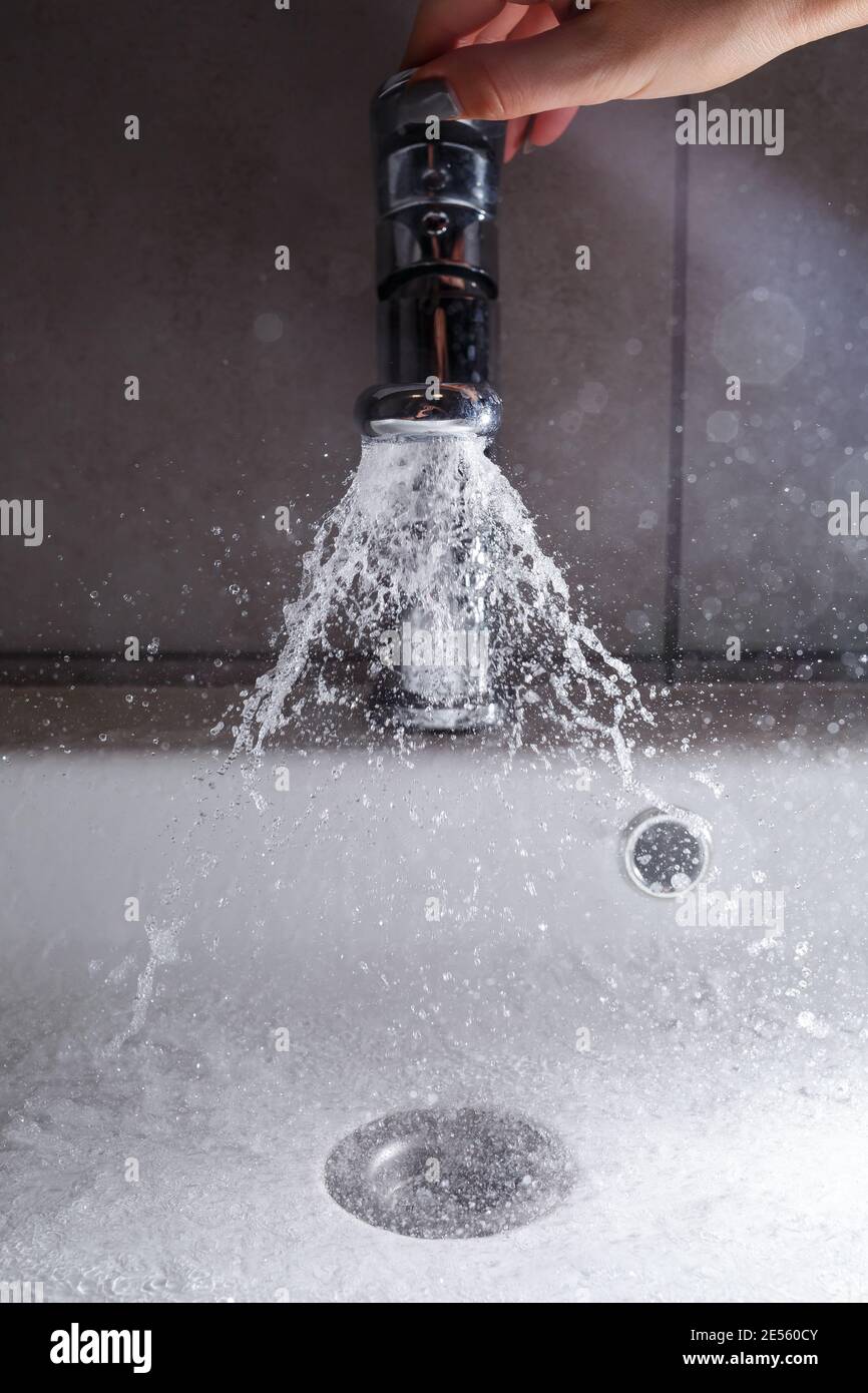 Broken water faucet in the bathroom sink. Water splashes from the