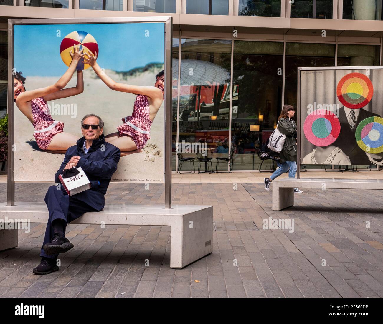 Mature man sitting on beach in front of retro poster near Kings Cross. Stock Photo