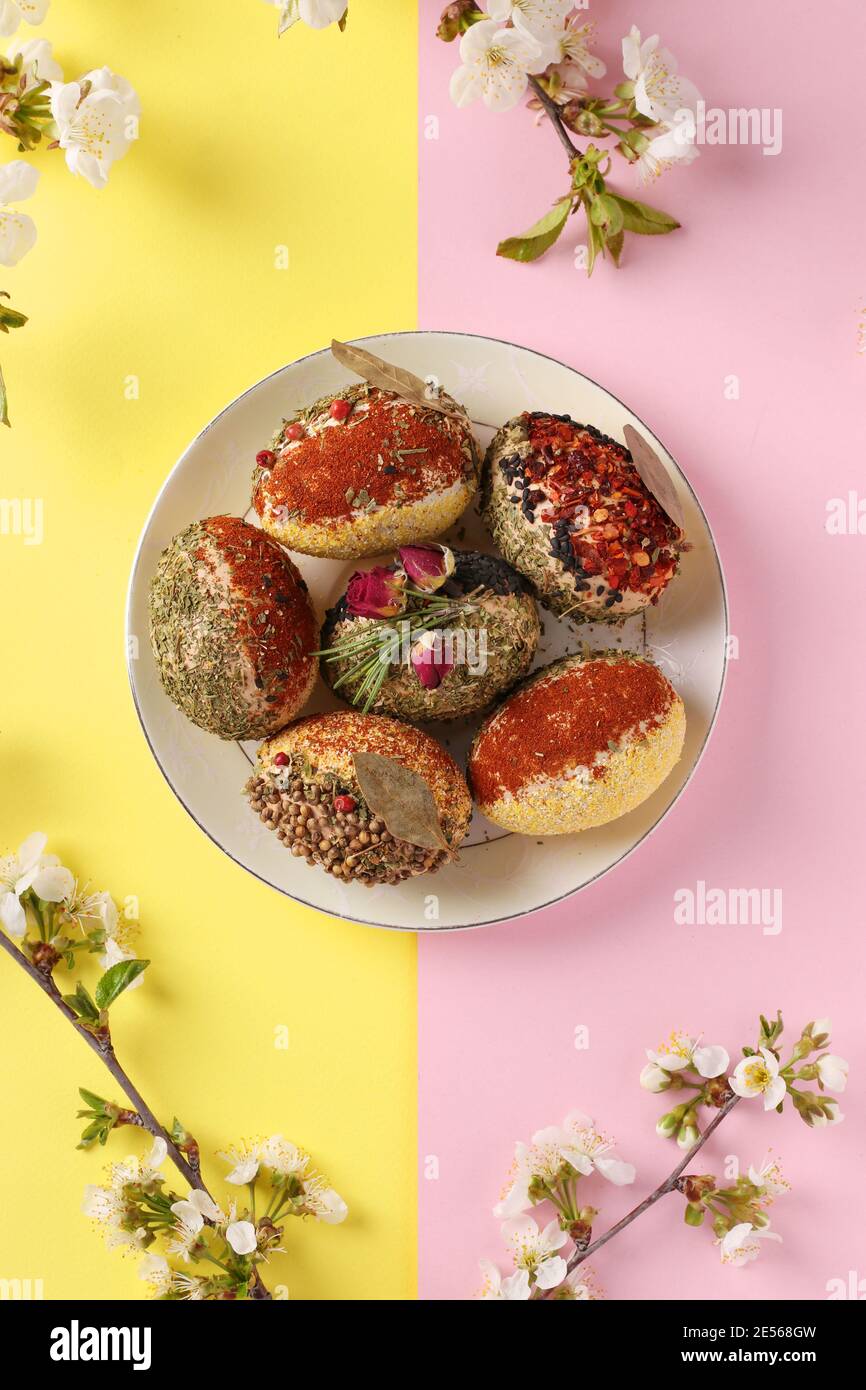 Easter concept with eggs decorated with different spices and cereals without dyes and preservatives on pink and yellow background. Vertical format. To Stock Photo