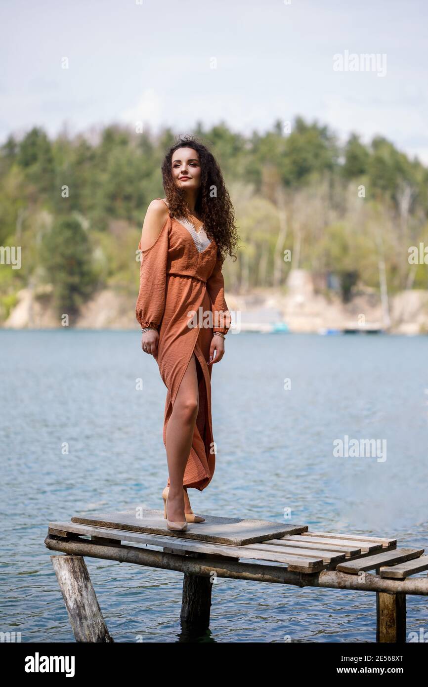 A young woman in a dress stands on wooden masonry in the middle of a ...