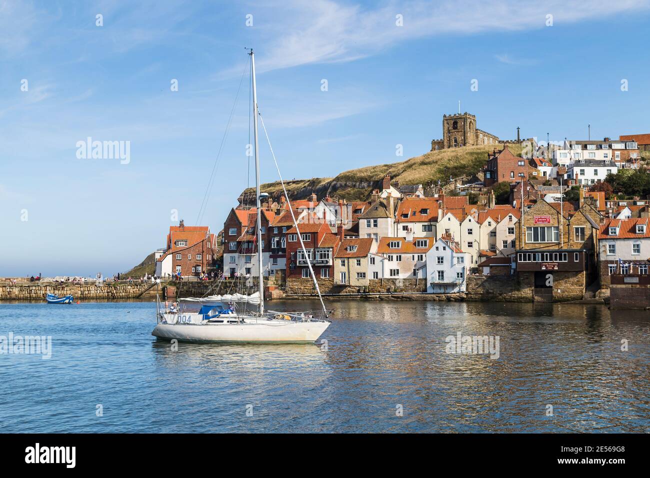 Yacht enters Whitby harbour under a blue sky Stock Photo - Alamy