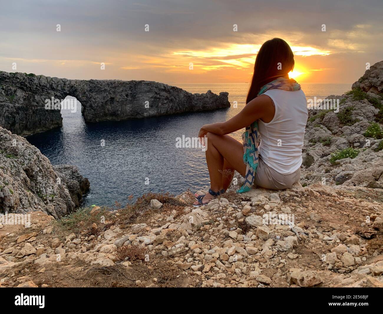 Girl enjoying the sunset in an idyllic place such as the Pont d'en Gil in menorca Stock Photo
