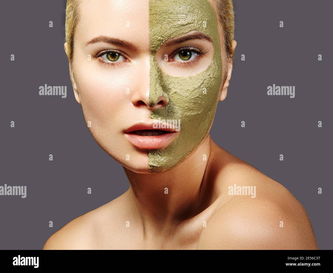 Beautiful Woman Applying Green Facial Mask. Beauty Treatments. Close-up Portrait of Spa Girl Apply Clay Facial mask on grey background Stock Photo