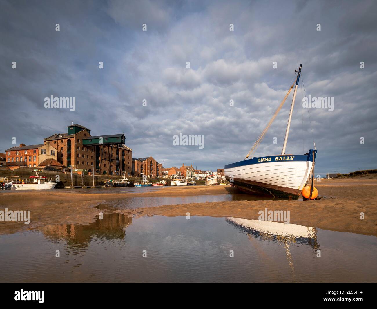 Wooden rowing boat on the sand banks of Wells harbour. Stock Photo