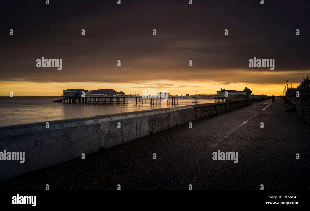 A dark winters morning at Cromer Pier as the sun comes up. Stock Photo