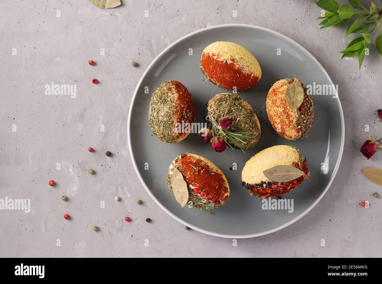 Easter eggs decorated with different spices and cereals without dyes and preservatives on a plate on a gray concrete background. View from above Stock Photo