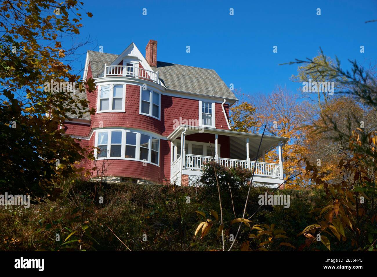 An old, red, wood, shingle Victorian era house on a hill. During fall, autumn in Harpers Ferry, West Virginia. Stock Photo