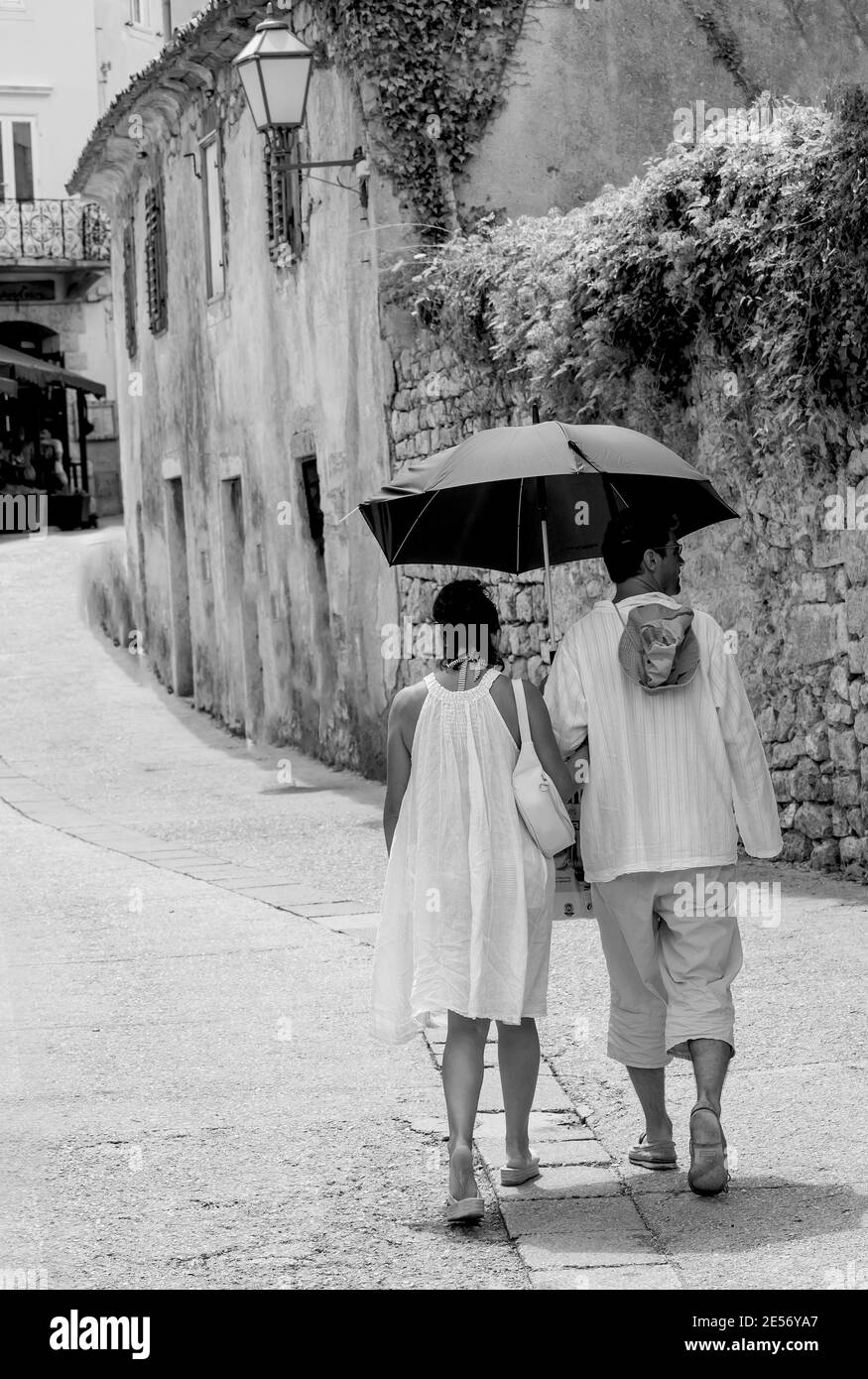 Loving couple with  black umbrella in a small street in Krk, Croatia Stock Photo