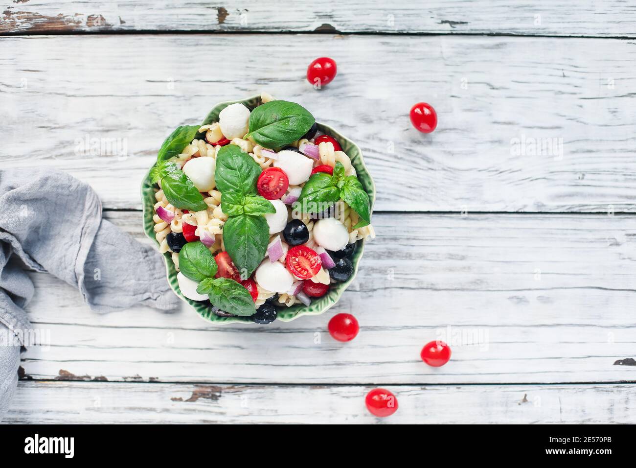 Italian pasta salad with fresh tomatoes, black olives, red onion mozzarella cheese balls, basil, and an olive oil dressing. Image shot from above. Stock Photo