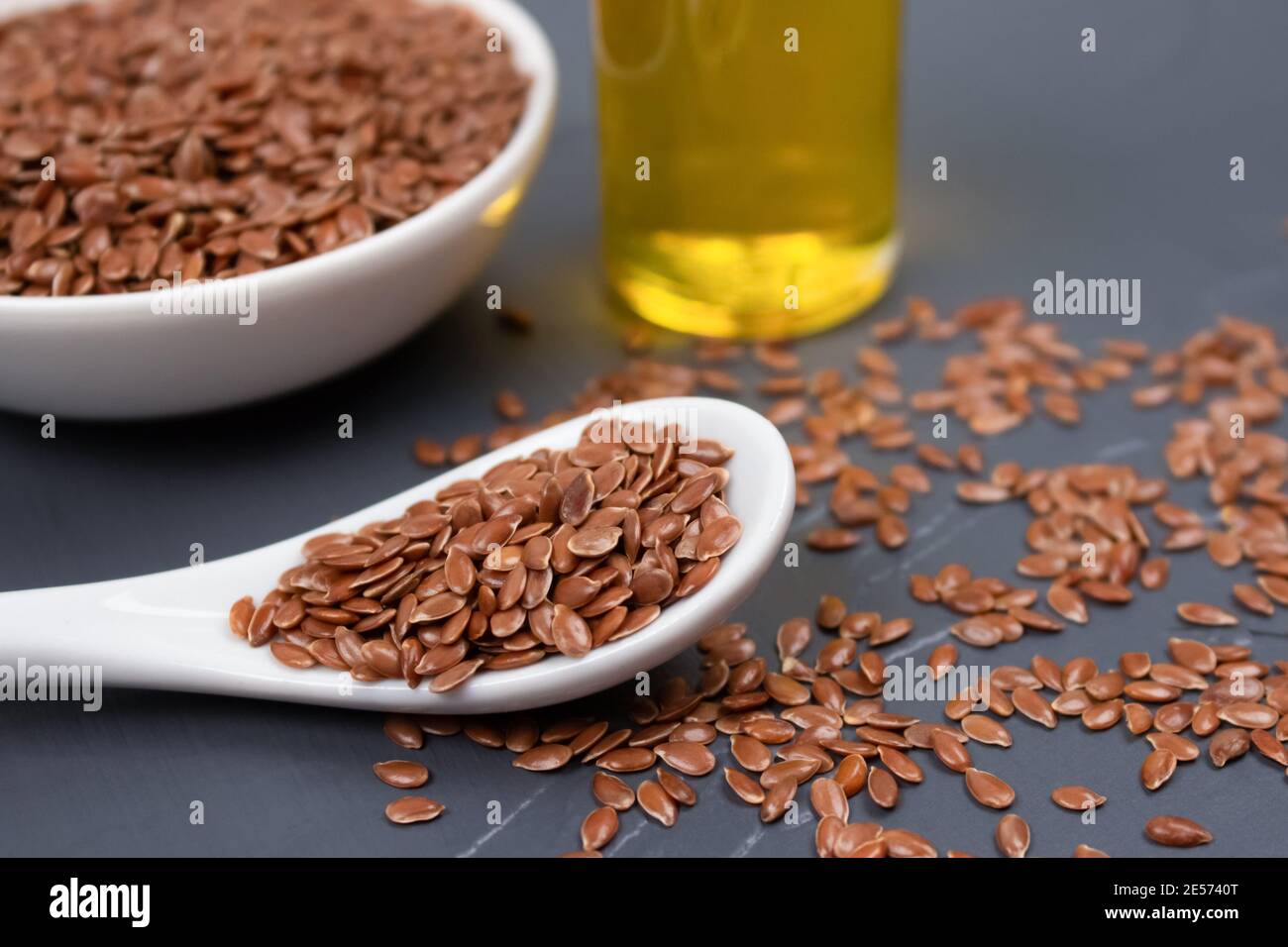Flax seeds with a bottle of flaxseed oil behind on gray background -  healthy eating or skin care concept. Top benefits of linseed in medicine  and Stock Photo - Alamy