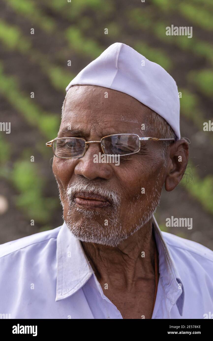 Abbigeri, Karnataka, India - November 6, 2013: Facial closeup of Siddappa Gidigena, peanut farmer is neat clean hat and shirt. Gold rimmed glasses cro Stock Photo