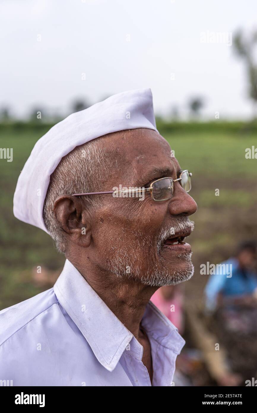 Abbigeri, Karnataka, India - November 6, 2013: Facial closeup of Siddappa Gidigena, peanut farmer is neat clean hat and shirt. Gold rimmed glasses on Stock Photo