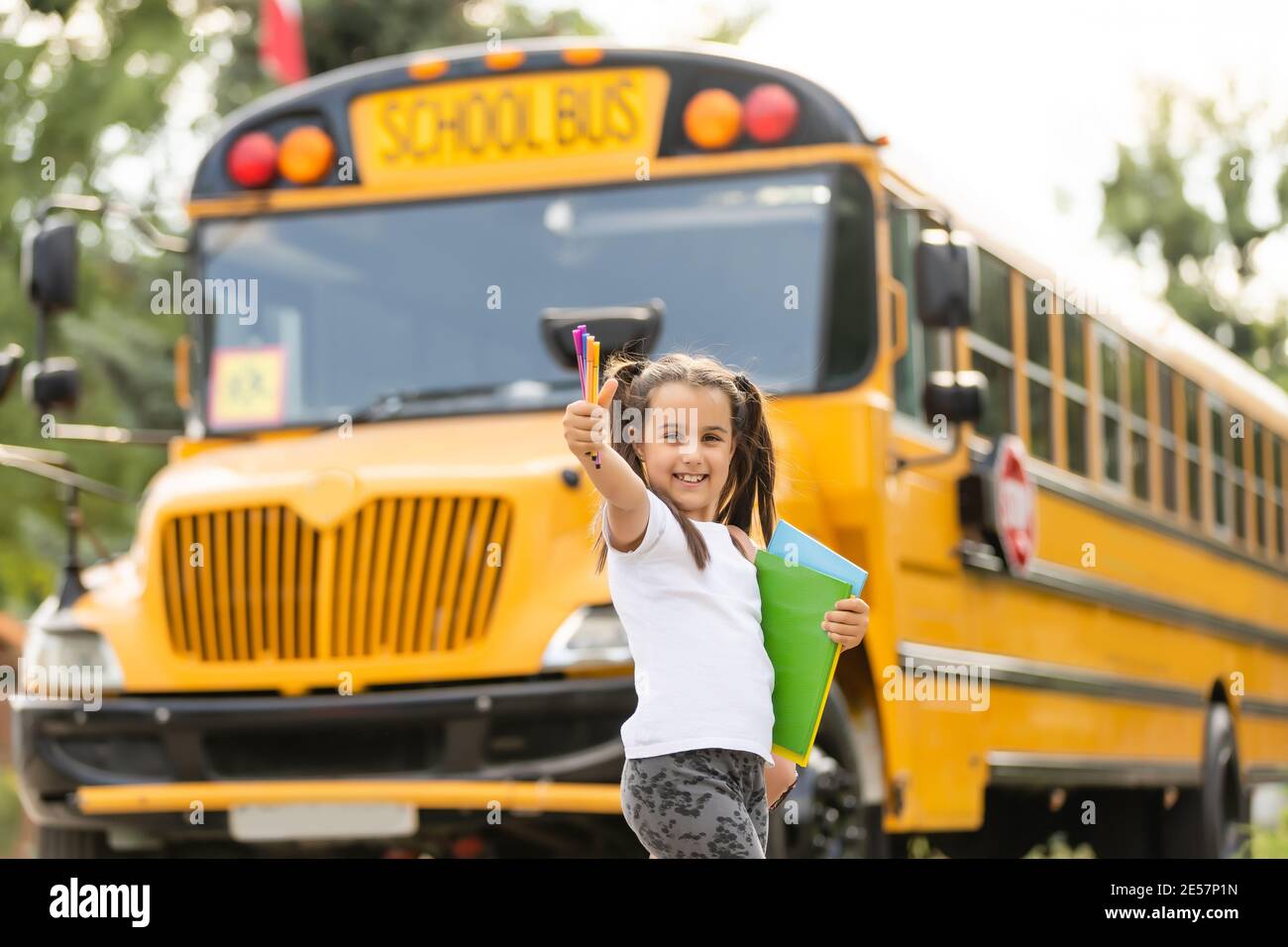 Cute girl with a backpack standing near bus going to school posing to camera pensive close-up Stock Photo