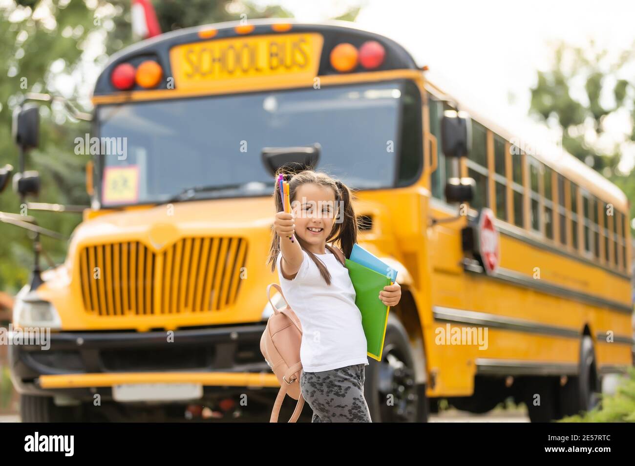 Girl with backpack near yellow school bus. Transport for students Stock