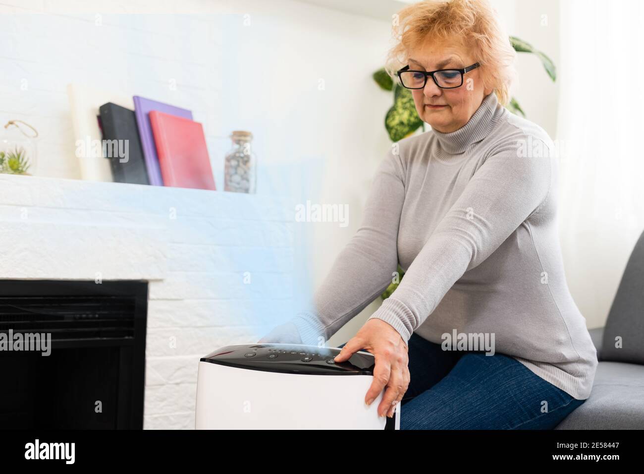 an elderly woman uses an air purifier in an apartment Stock Photo Alamy