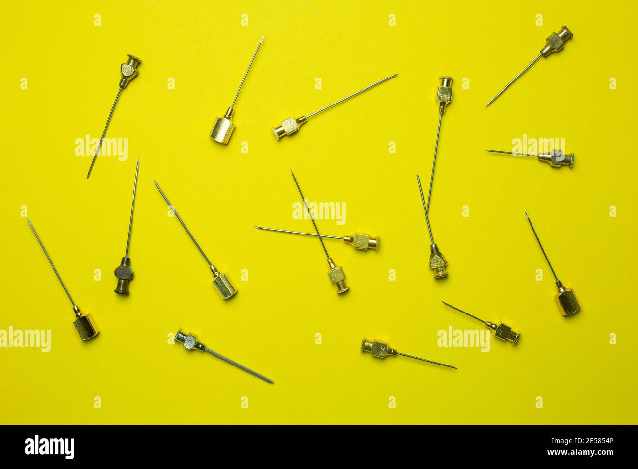 A Set of old syringe needles in different sizes and thicknesses. Yellow background Stock Photo