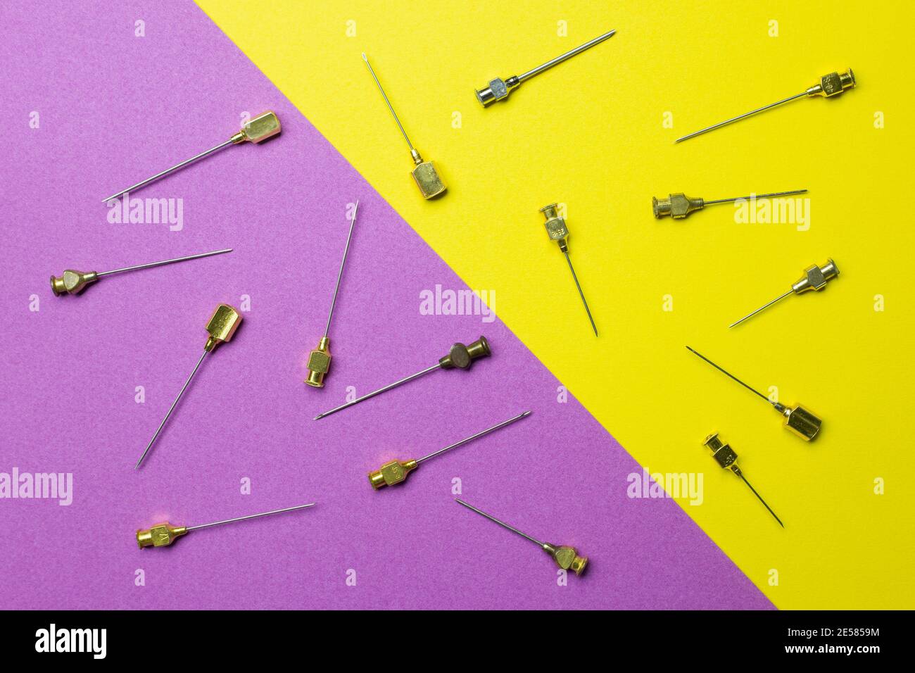 A Set of old syringe needles in different sizes and thicknesses. Yellow and violet background Stock Photo