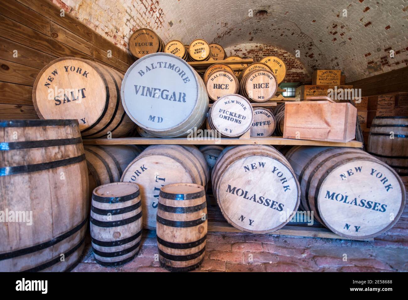Barrels labeled 'vinegar, salt beef, rice, flour, salt, molasses, pickled onions  and coffee' fill a recreated ration storage room at Fort Macon State Stock Photo