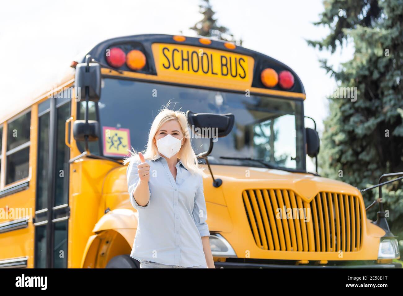 Portrait of beautiful female masked teacher near school bus Stock Photo ...