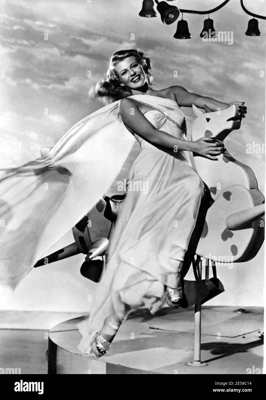 1948 c., USA : The movie actress  RITA HAYWORTH  ( 1918 - 1987 ) - CINEMA - FILM - portrait - ritratto - vento - wind - giostra - luna park - lunapark - luna-park - merry-go-round - merrygoround - mery go round - cavallo - horse - smile - sorriso - spalle - shoulders - sandali - sandals  ----  Archivio GBB Stock Photo