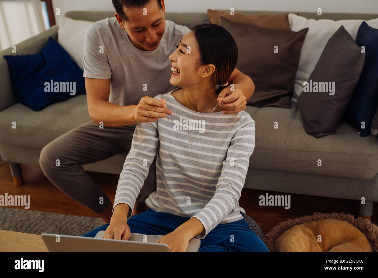 Young man giving his girlfriend a necklace as present. Asian woman