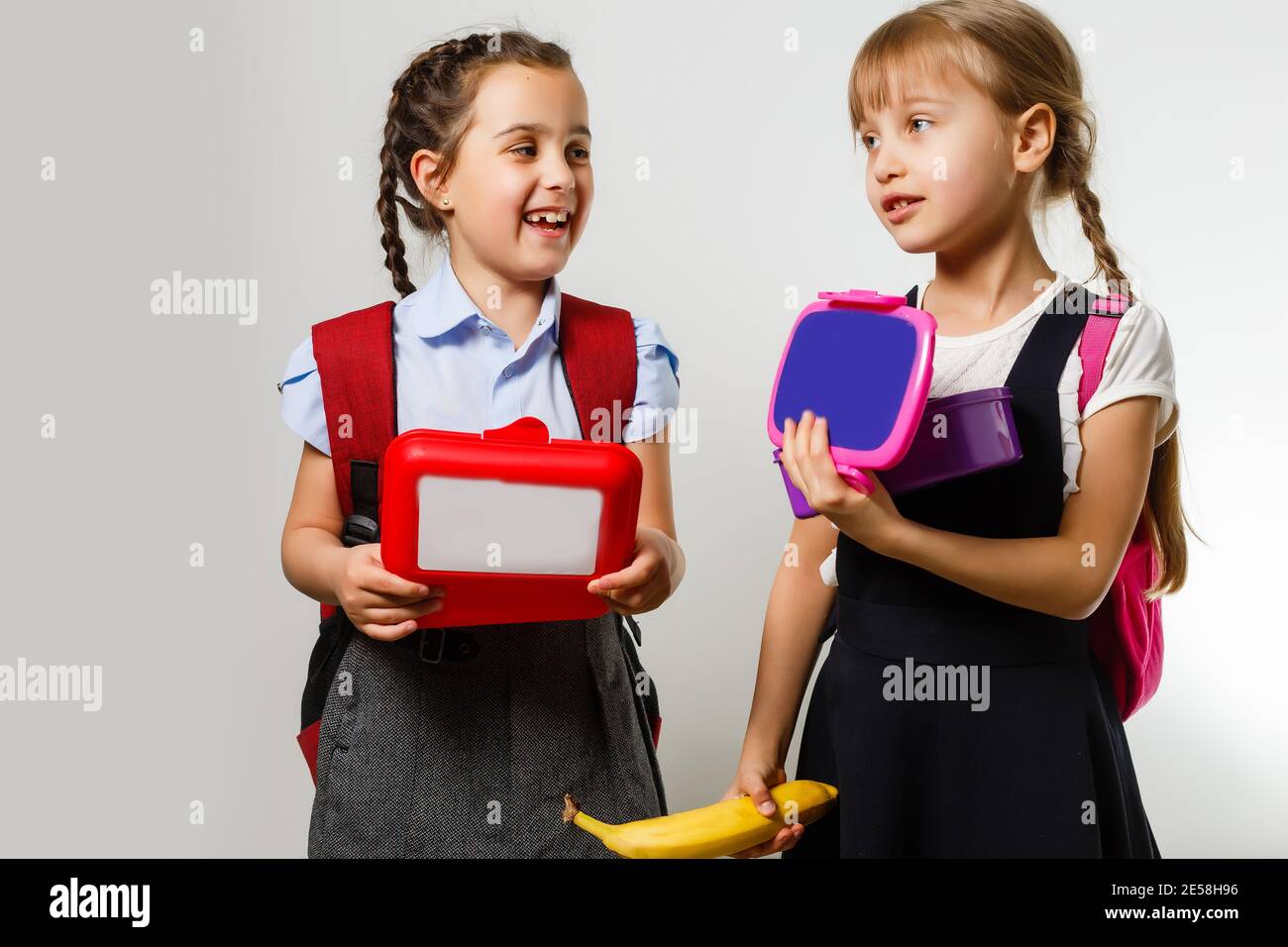 Pupils of primary school with lunch-boxes in hands. Girls with ...