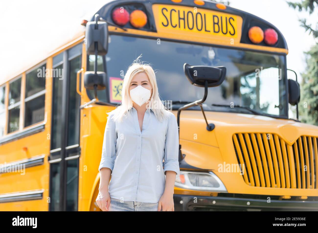 Portrait of beautiful female masked teacher near school bus Stock Photo ...