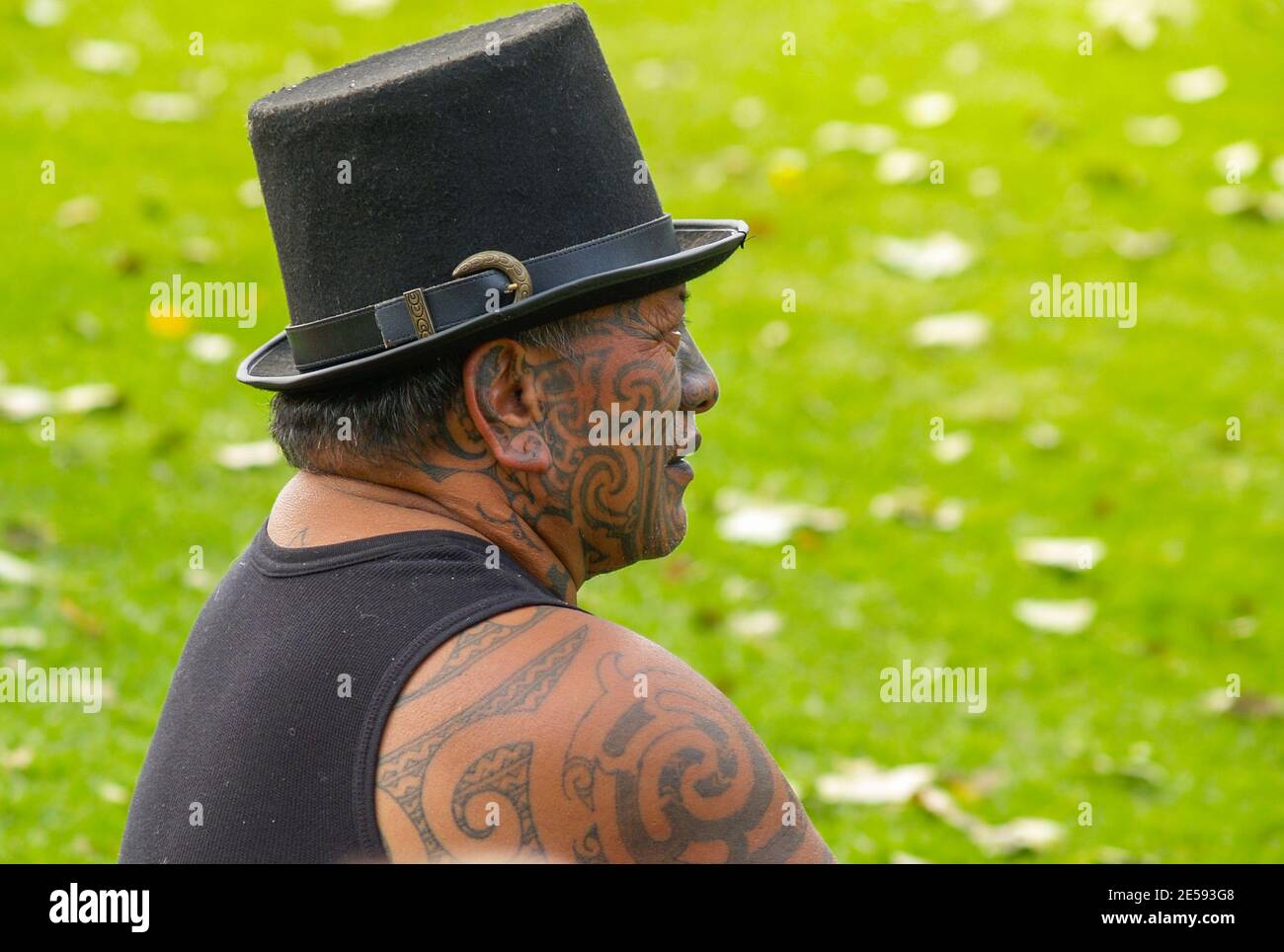 TAURANGA, NEW ZEALAND - April 3 2020; ; Maori male with traditionally heavily tattooed face and arm wearing top hat profile portrait. Stock Photo
