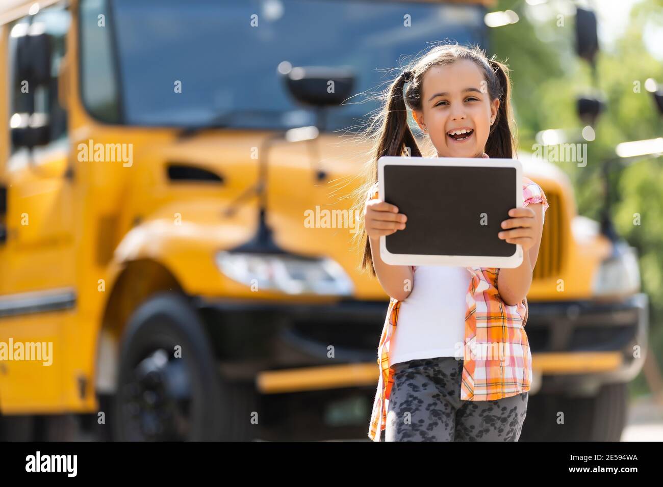 Little girl standing by a big school bus door with her backpack Stock