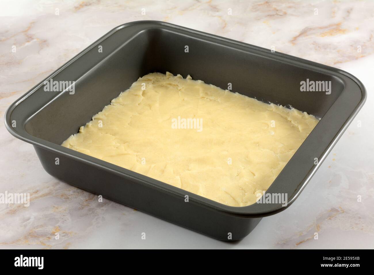 Raw dough for crust for dessert fruit bars in nonstick baking pan Stock Photo