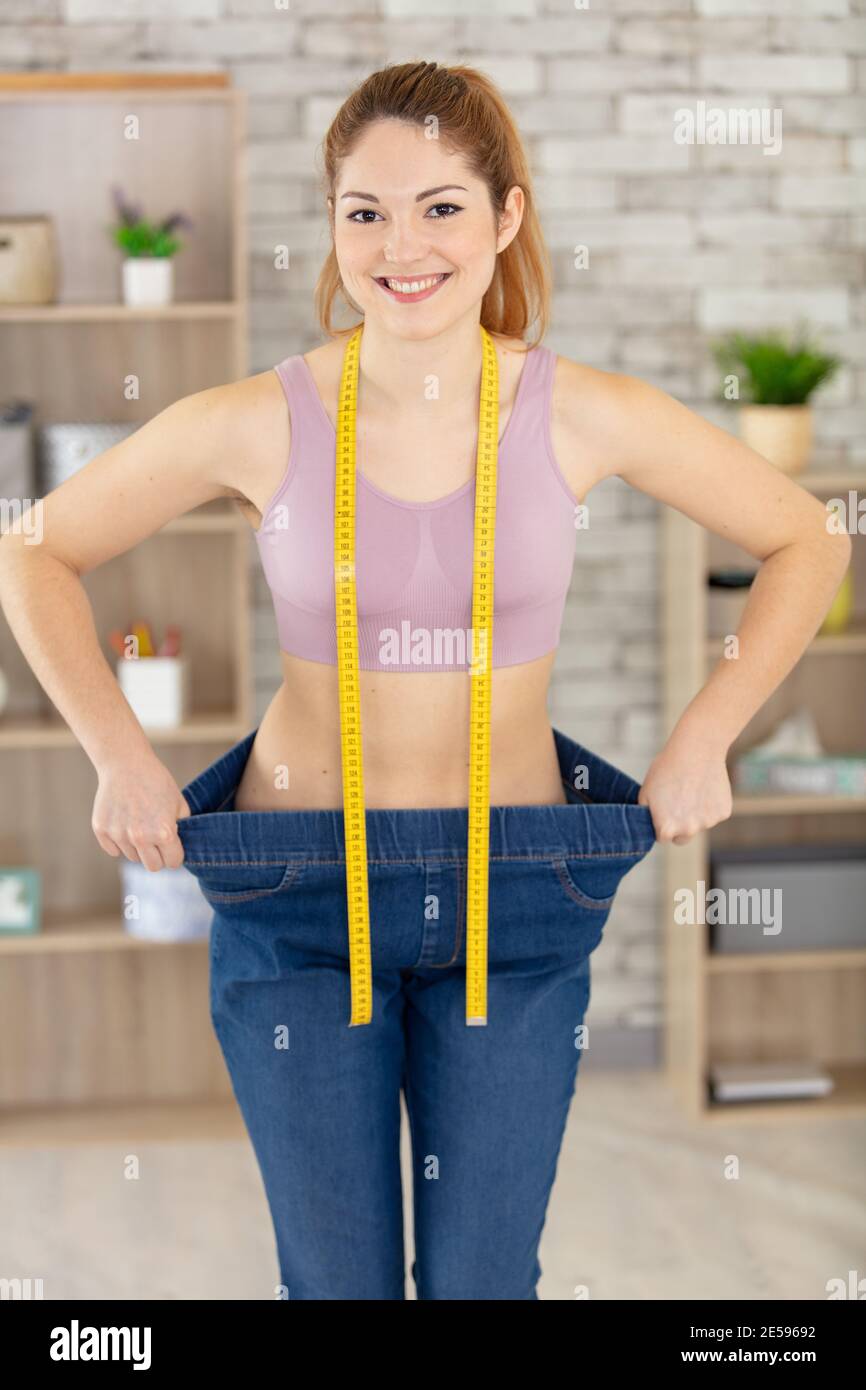 girl pulling her big jeans and showing weight loss Stock Photo