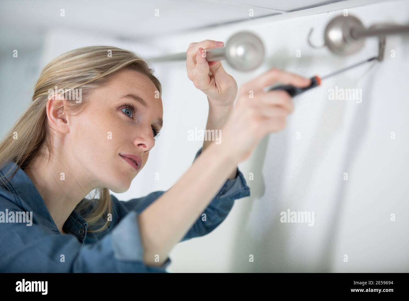 woman installing blinds with screwdriver Stock Photo