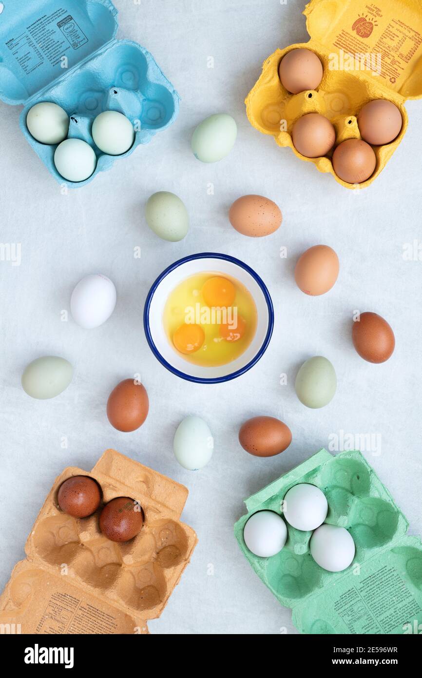 Different types of free range eggs with raw eggs in a bowl and shells on a white background Stock Photo