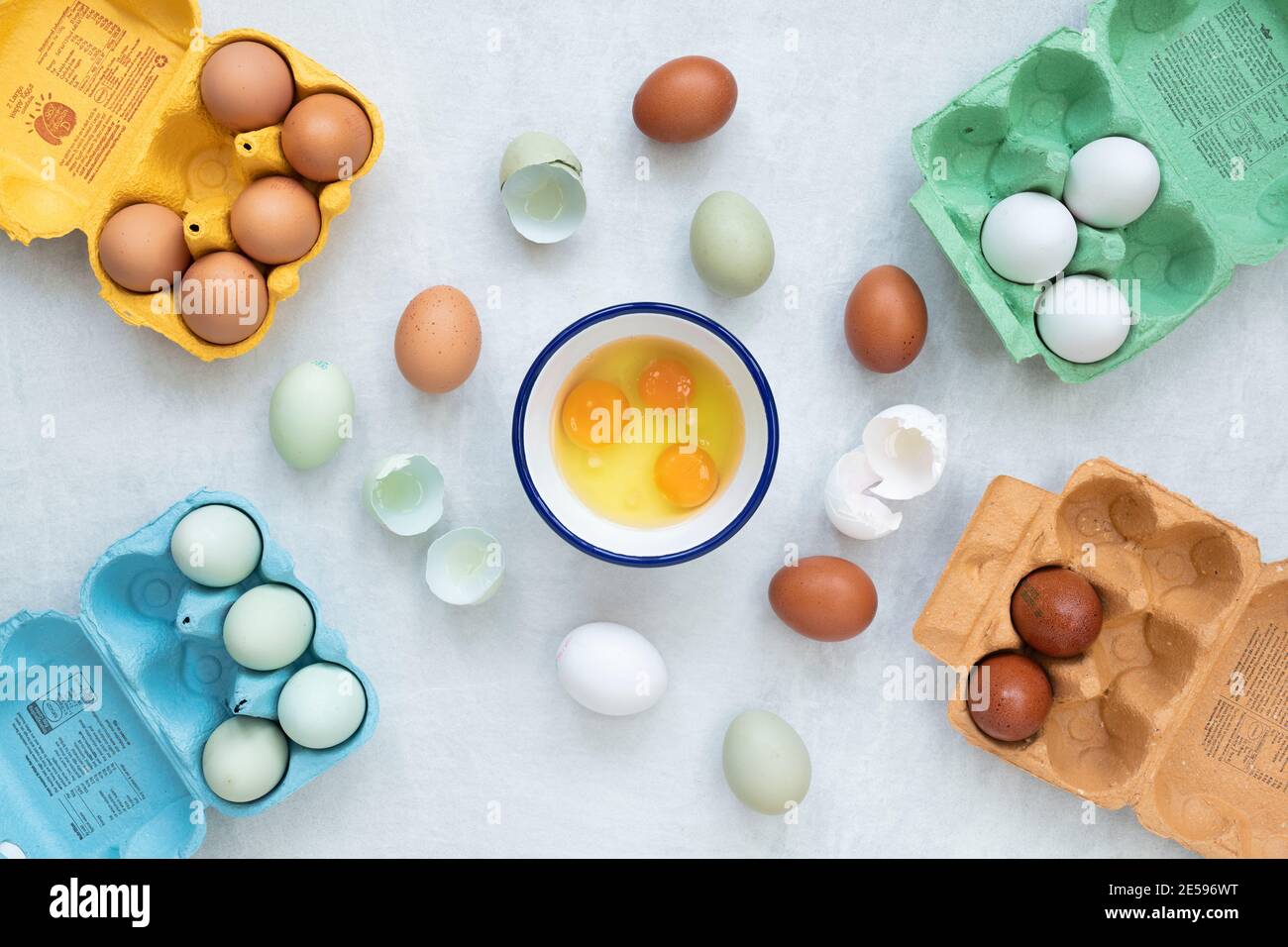 Different types of free range eggs with raw eggs in a bowl and shells on a white background Stock Photo
