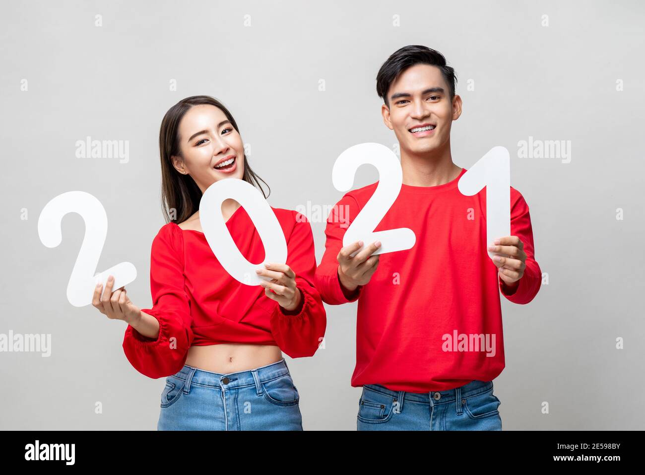 Smiling happy Asian couple and showing number 2021 for new year concept on light gray studio background Stock Photo