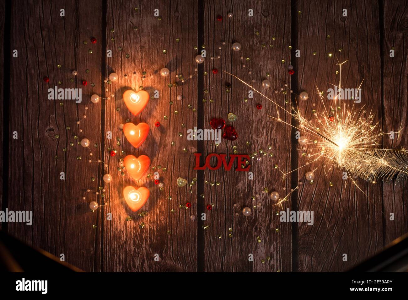candles, glowing hearts, sparklers, on a dark wooden background. Background for Valentine's Day