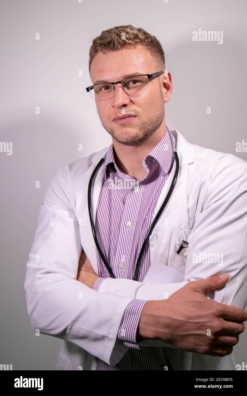 Serious attractive male doctor wearing white lab coat looking at camera