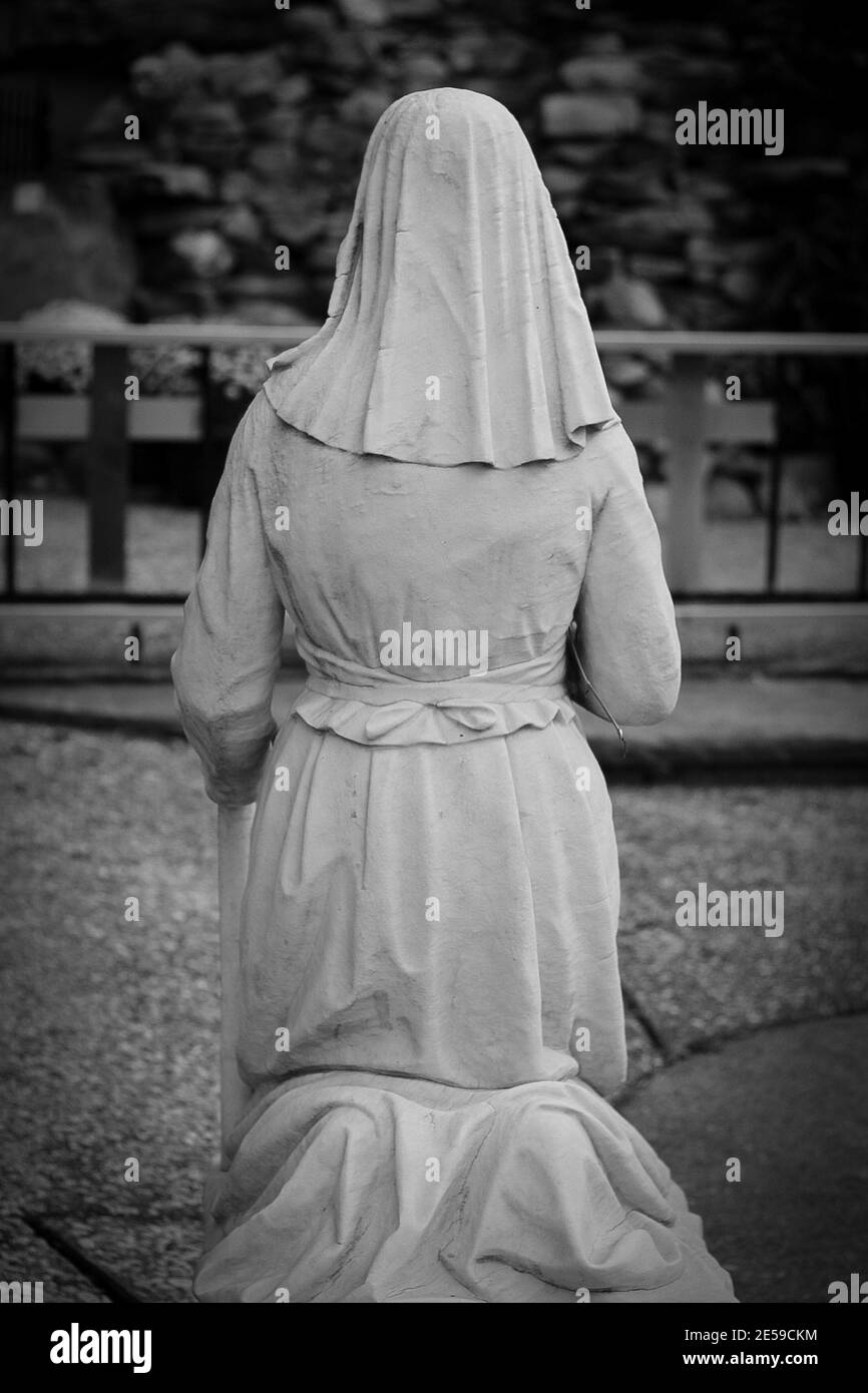 Vertical shot of the back of kneeling Virgin Mary Statue Stock Photo