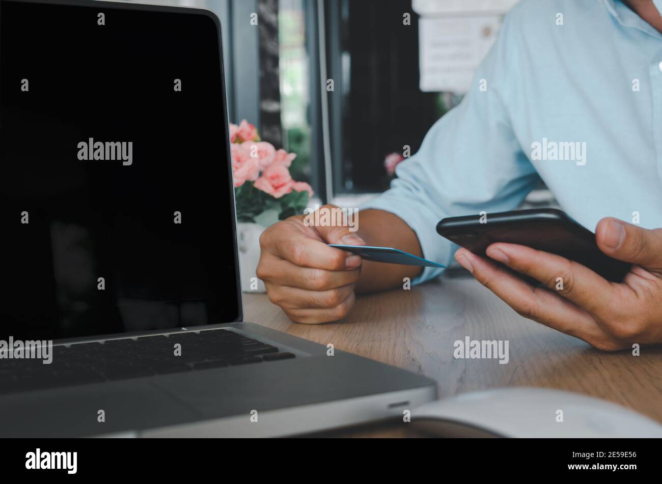 business man hand using mobile smart phone and credit card  with computer laptop on table.Shop online and make payment transactions business concept Stock Photo