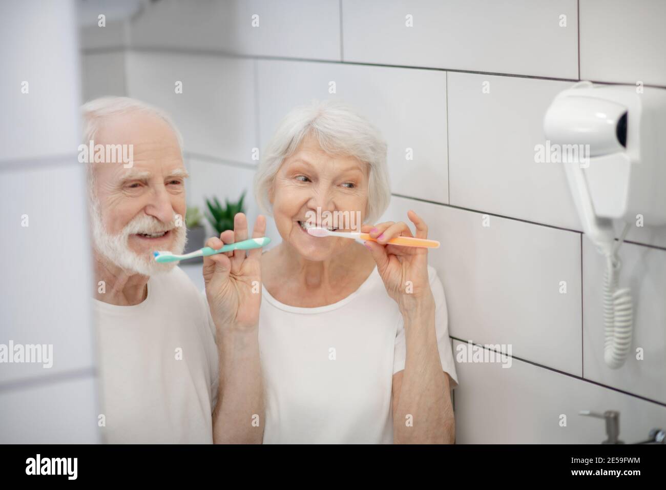 Elderly couple brushing their teeth together and feeling good Stock Photo
