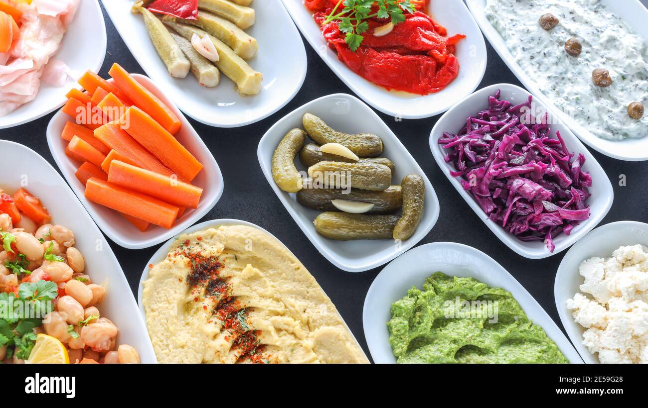 Top view of traditional Turkish and Greek vegetable dinner meze table. Turkish Cuisine Cold Appetizers ( with olive oil) in white plates. Stock Photo