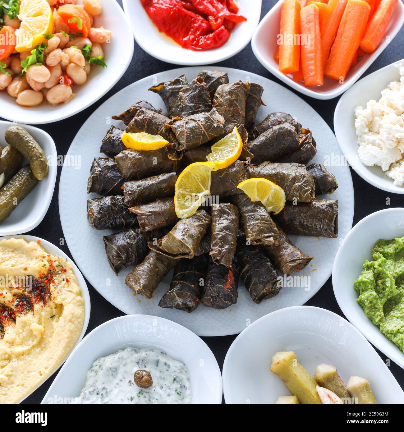 Traditional Turkish and Greek vegetable dinner meze table. with Stuffed Grape Leaves, olives, colorful hummus, Cold Appetizers ( with olive oil) Stock Photo