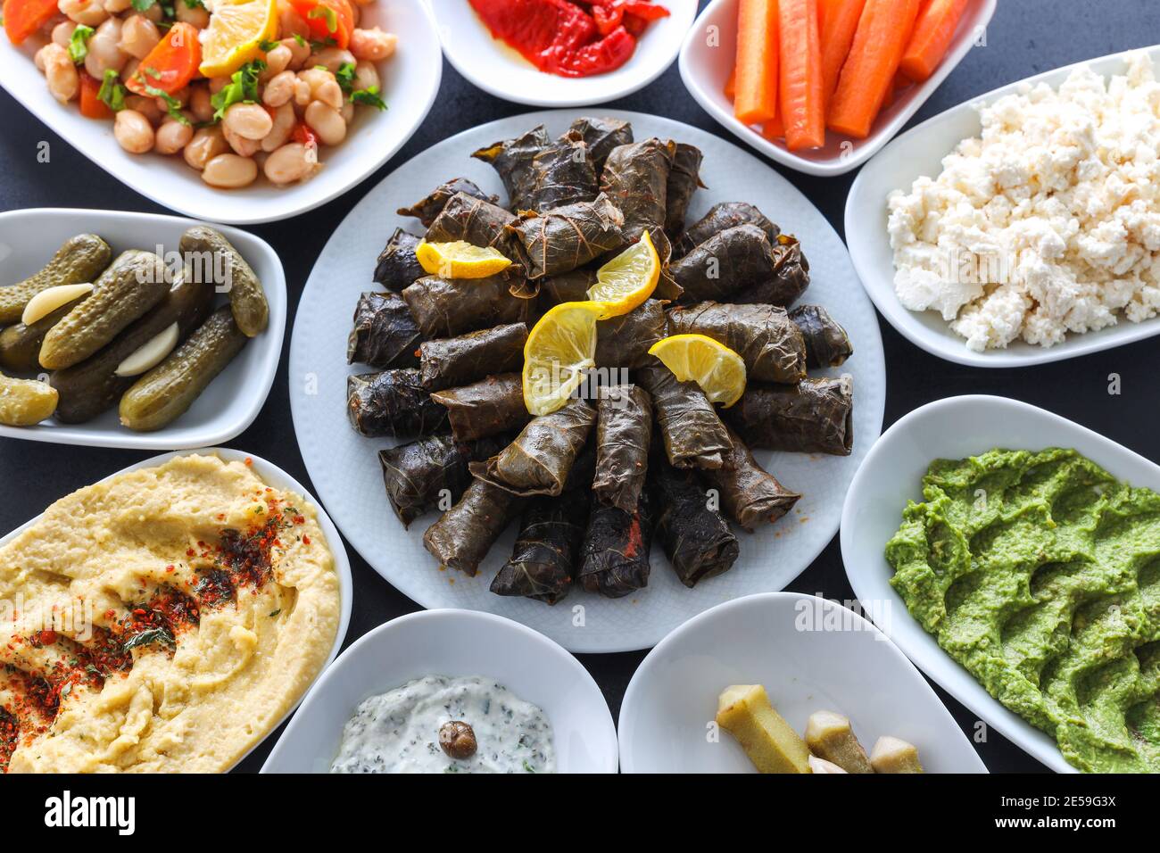 Traditional Turkish and Greek vegetable dinner meze table. with Stuffed Grape Leaves, olives, colorful hummus, Cold Appetizers ( with olive oil) Stock Photo