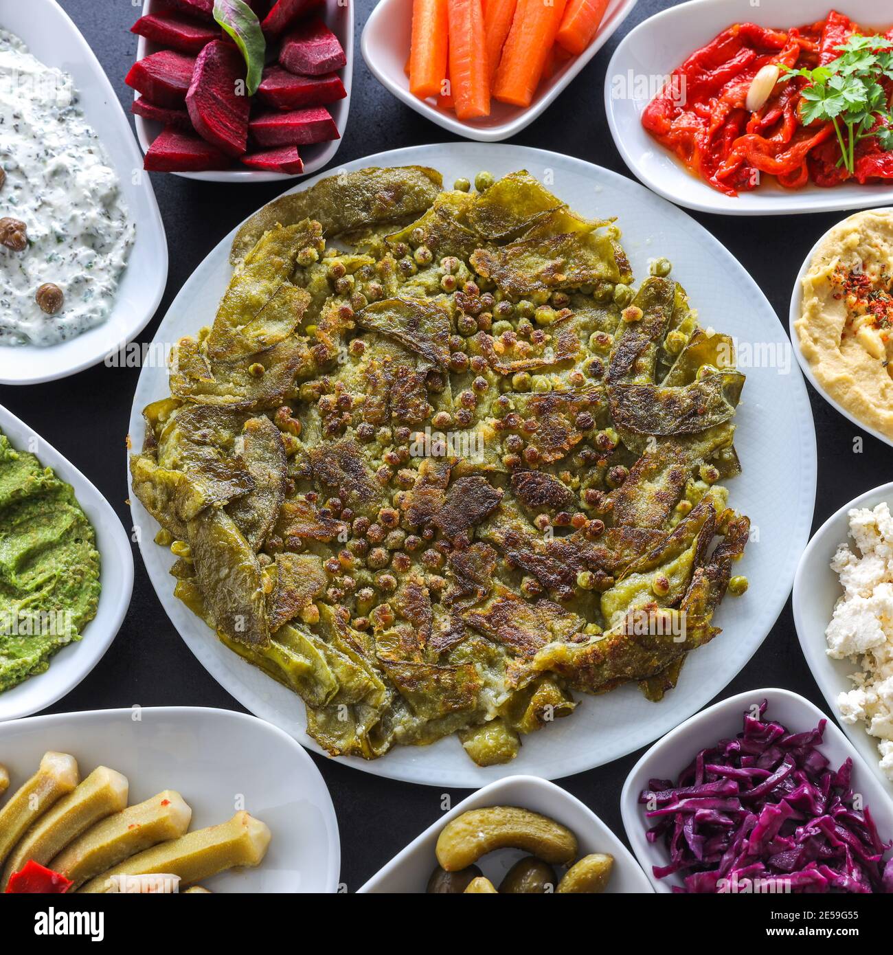 Traditional Turkish vegetable dinner meze table. Fried green beans with Stuffed Grape Leaves, colorful hummus, Cold Appetizers ( with olive oil) Stock Photo