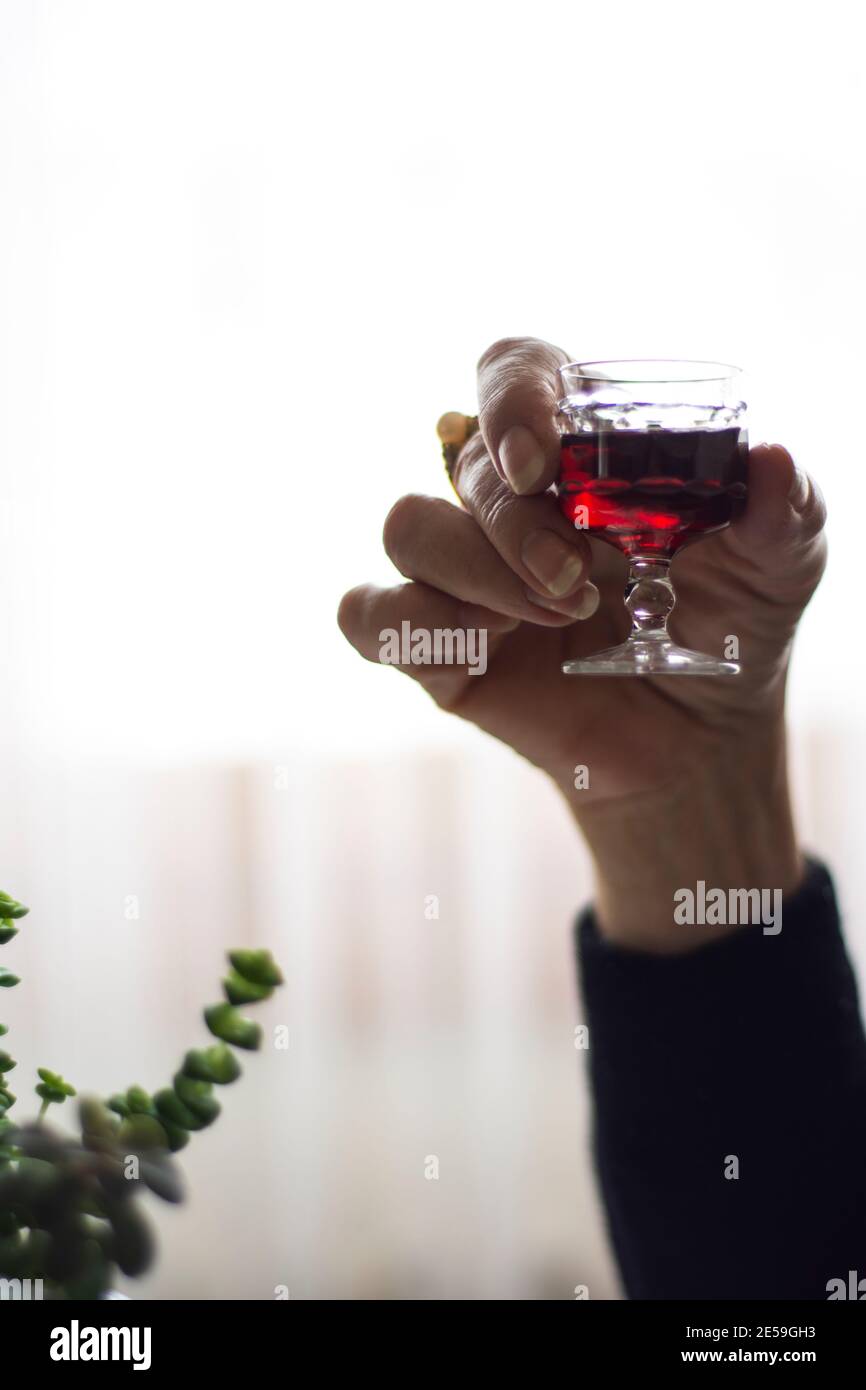 Liquor glass in woman hand, selective focus on glass. Vintage photo. Stock Photo