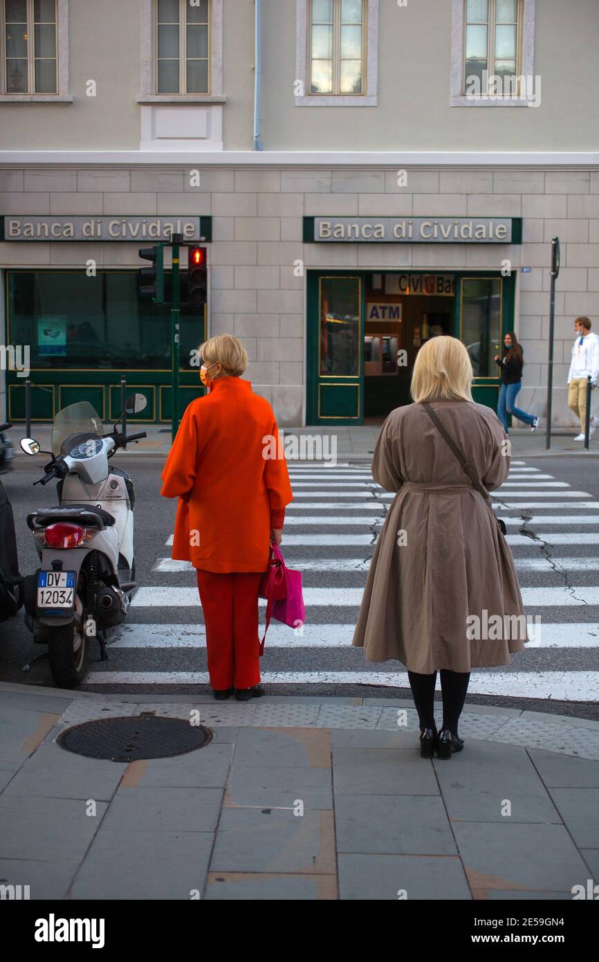 Trieste, Italy - October, 08: Two women standing on the side of the road before crossing the pedestrian crossings   on October 08, 2020 Stock Photo