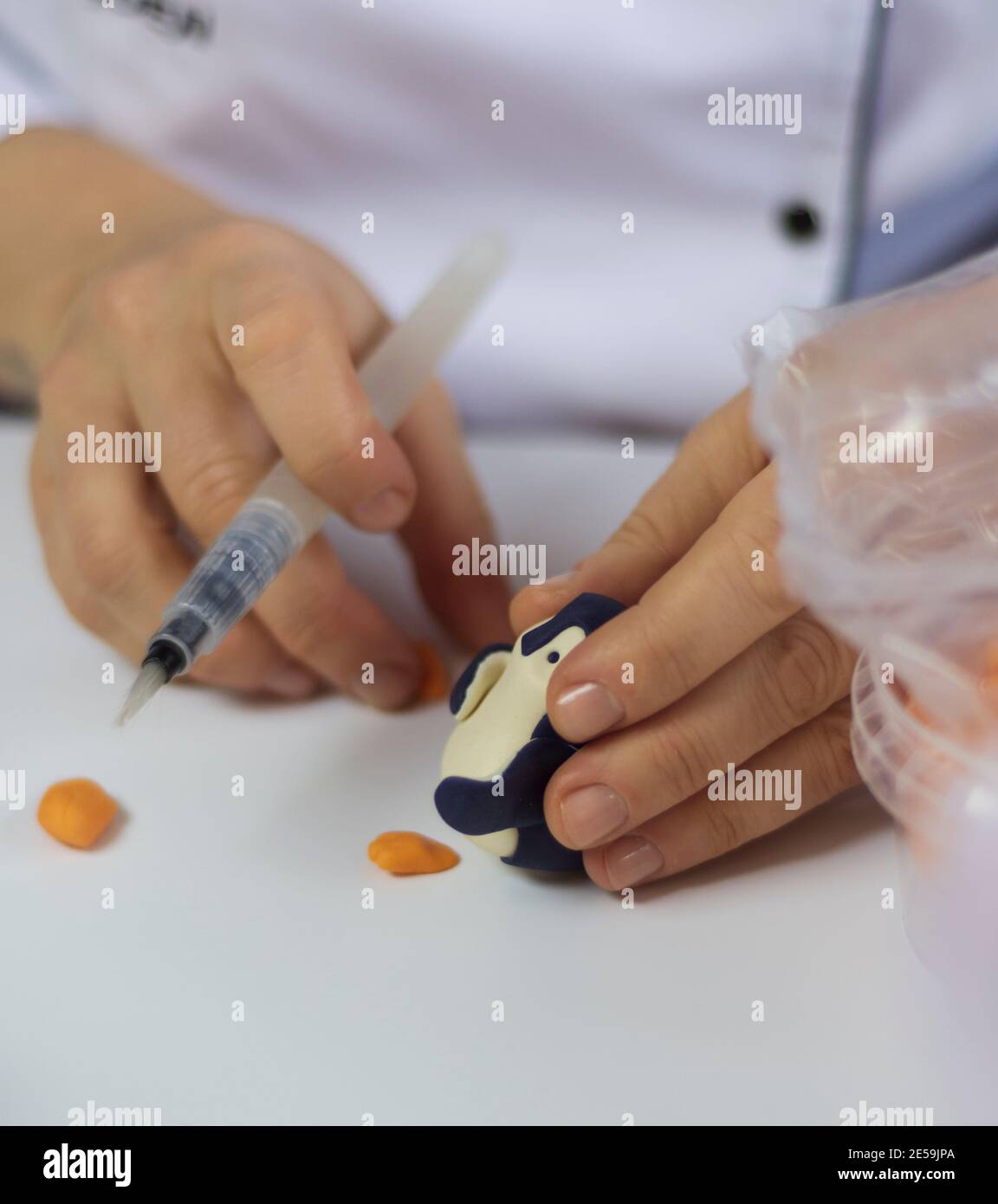 Cake decorating process. Baker uses tools to sculpt fondant patterns ...