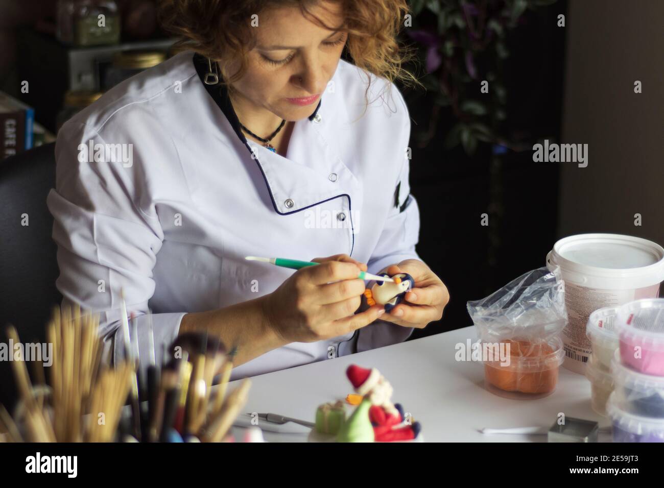 Cake decorating process. Baker uses tools to sculpt fondant patterns: edible art, cake design, cake decorating. Selective focus front tools and hand Stock Photo